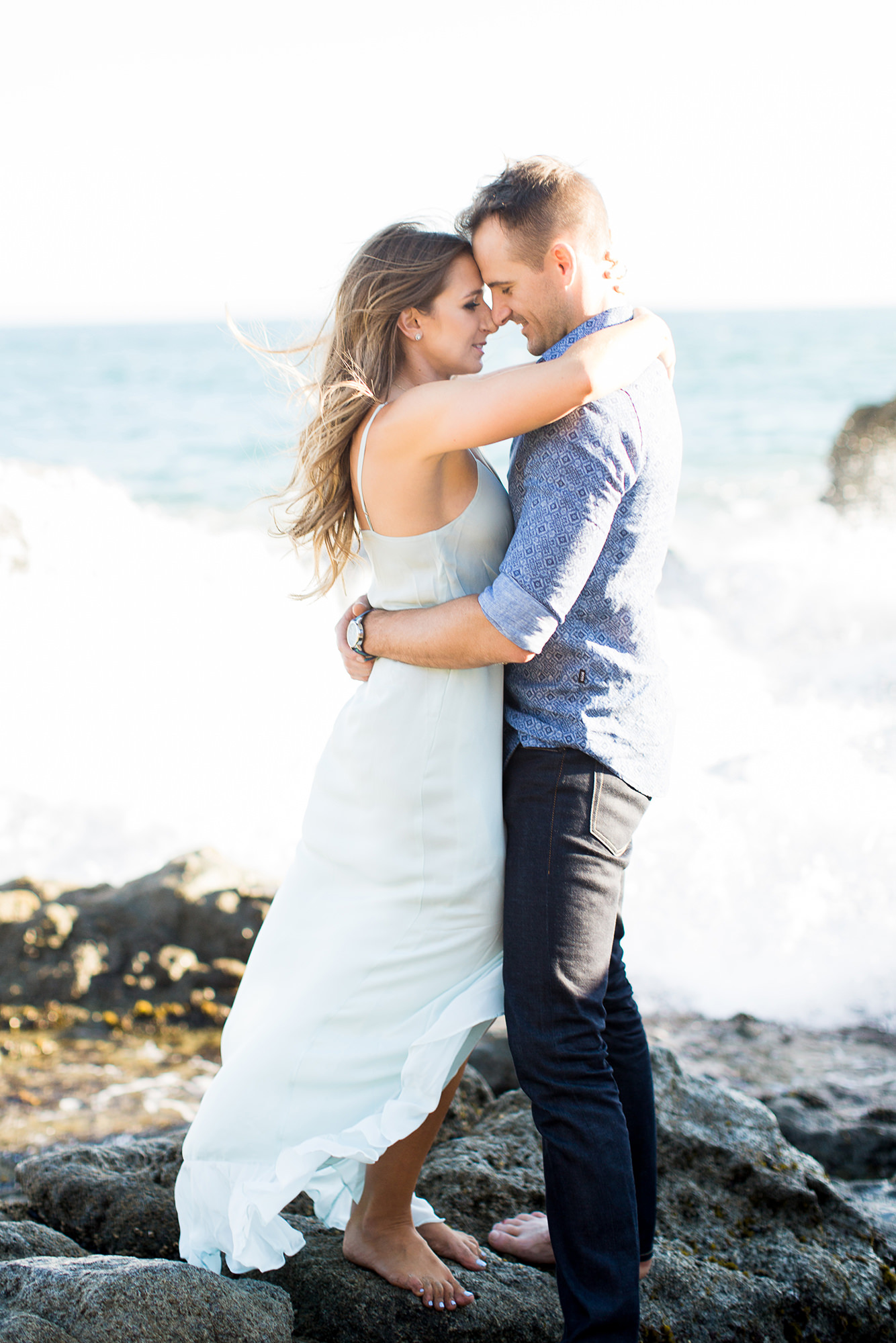 engagement photos on beach with wave crashing behind couple